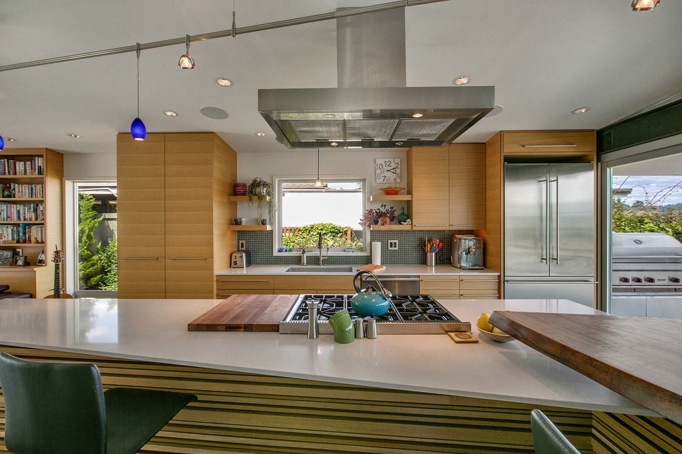 Mid-sized modern l-shaped open plan kitchen in Seattle with a single-bowl sink, flat-panel cabinets, light wood cabinets, quartzite benchtops, green splashback, glass tile splashback, stainless steel appliances, slate floors and with island.
