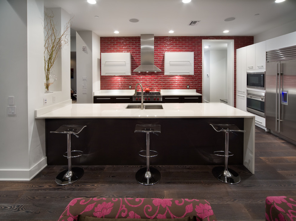 Photo of a contemporary kitchen in Tampa with an undermount sink, flat-panel cabinets, white cabinets, red splashback and stainless steel appliances.