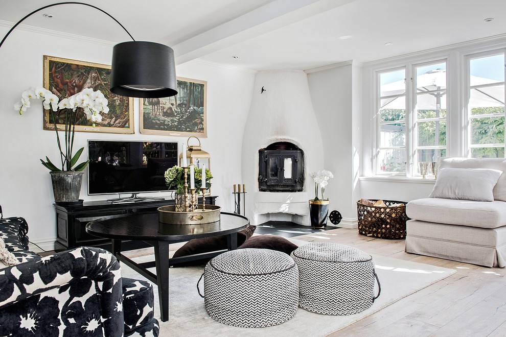 This is an example of a mid-sized scandinavian enclosed living room in Malmo with white walls, light hardwood floors, a corner fireplace, a plaster fireplace surround and beige floor.