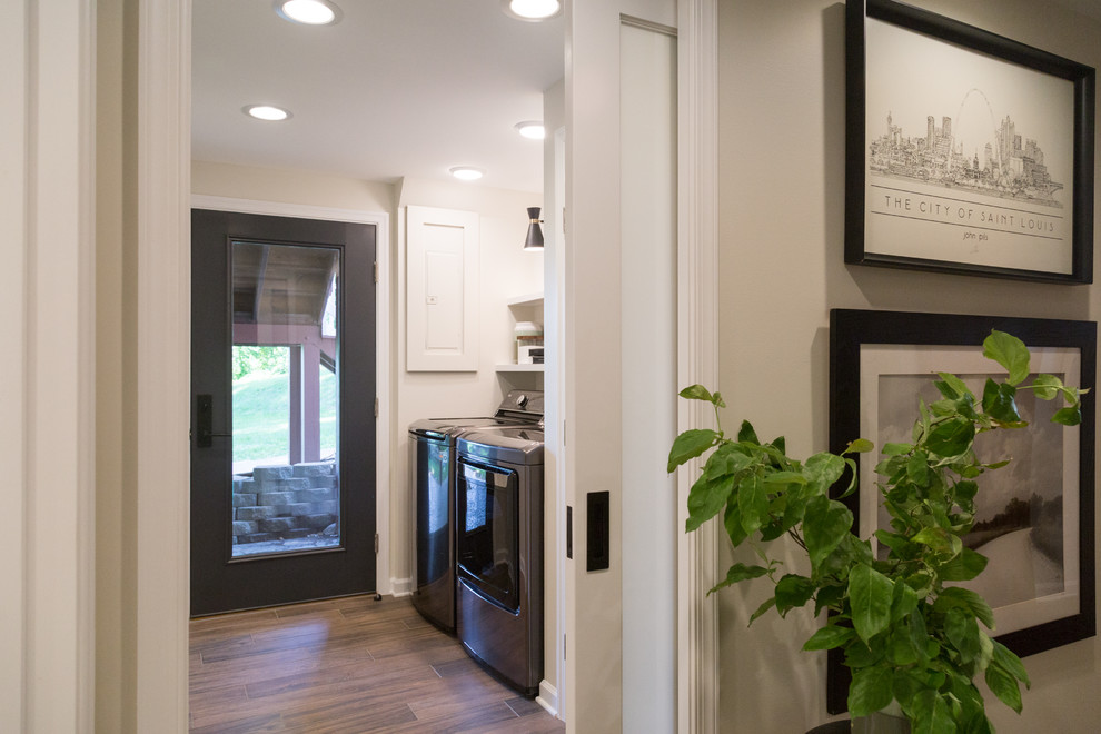 Example of a trendy medium tone wood floor and brown floor dedicated laundry room design in Other with open cabinets, white cabinets, beige walls and a side-by-side washer/dryer