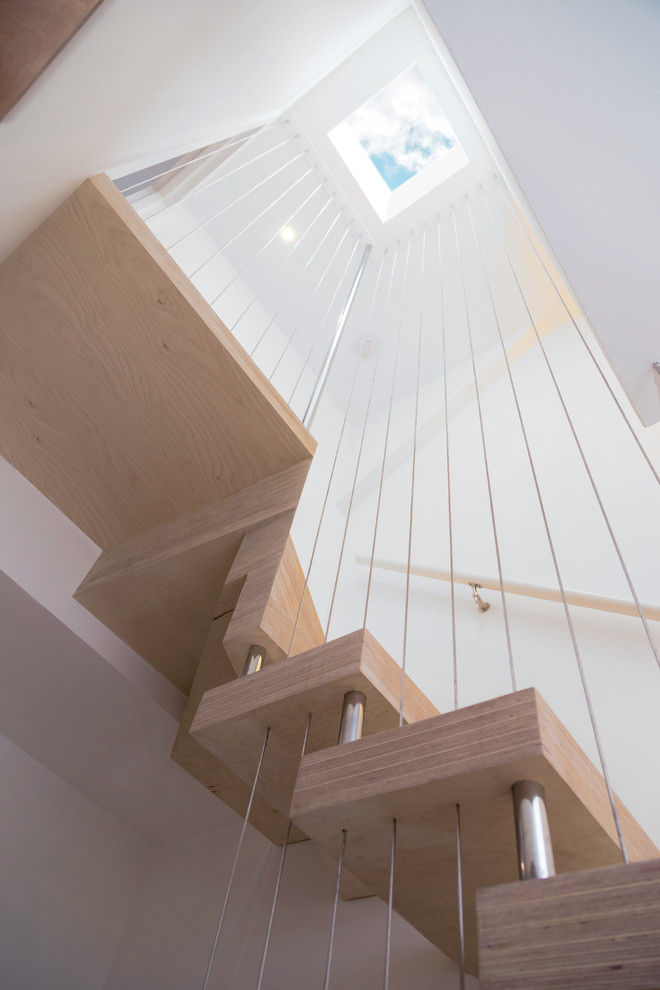 Imagen de escalera en U actual de tamaño medio sin contrahuella con escalones de madera y barandilla de cable