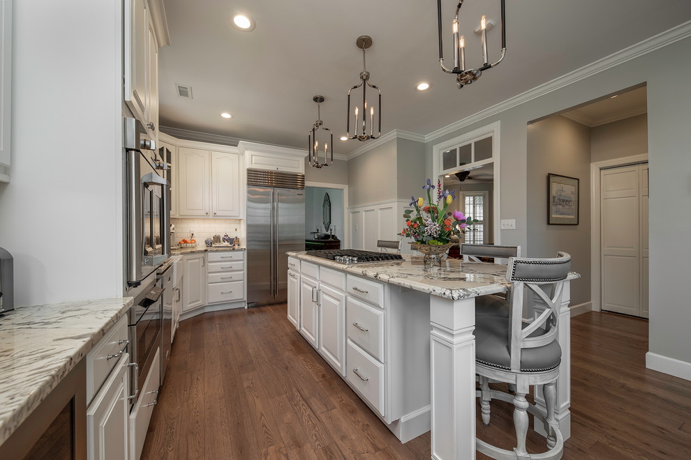 Traditional eat-in kitchen in Other with a farmhouse sink, raised-panel cabinets, white cabinets, granite benchtops, subway tile splashback, stainless steel appliances and with island.