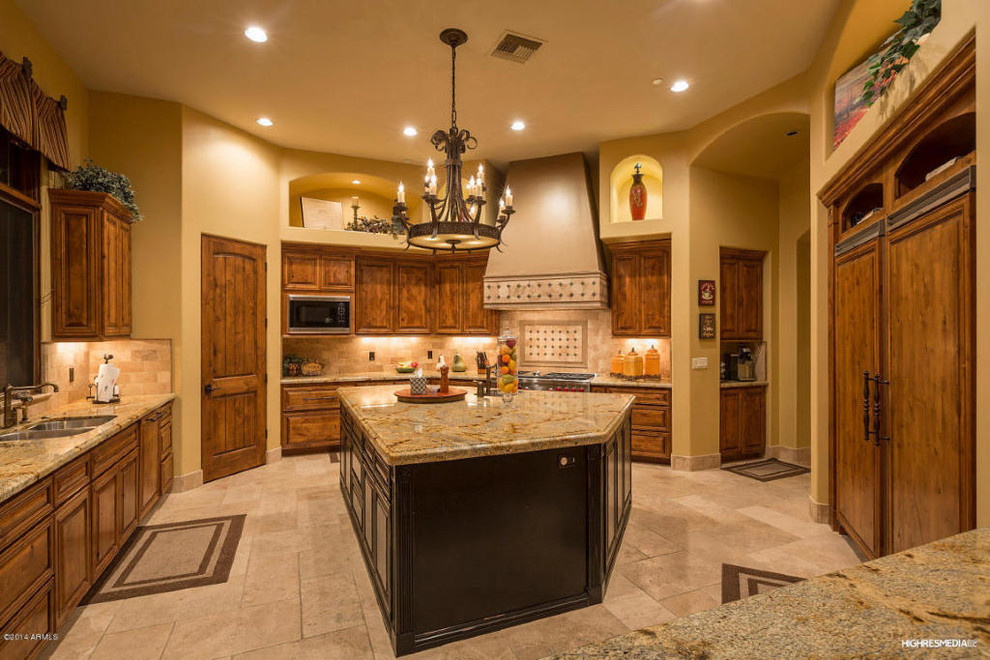 Example of a large transitional u-shaped travertine floor open concept kitchen design in Phoenix with an undermount sink, raised-panel cabinets, medium tone wood cabinets, granite countertops, beige backsplash, stone tile backsplash, paneled appliances and two islands