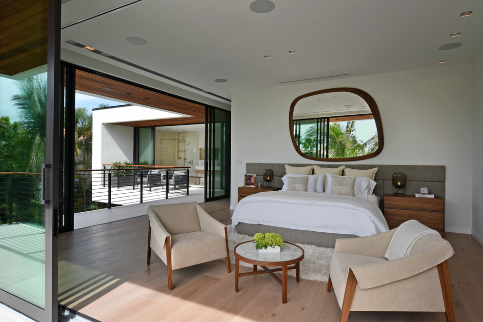 This is an example of a contemporary bedroom in Miami with white walls, medium hardwood floors and brown floor.