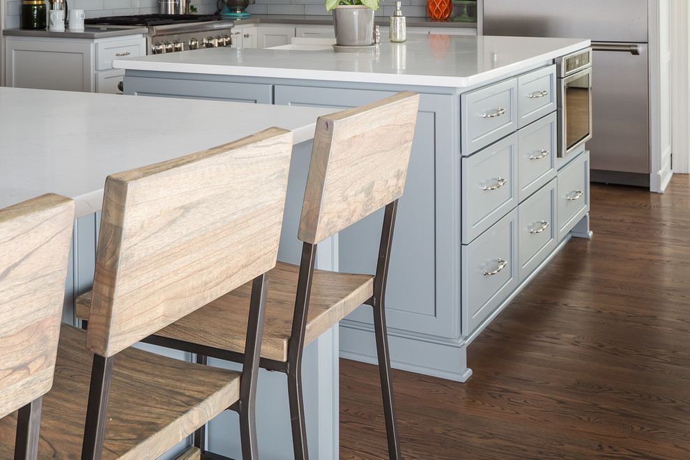 Home design - huge transitional galley medium tone wood floor home design idea in Raleigh with a farmhouse sink, flat-panel cabinets, white cabinets, quartz countertops, gray backsplash, ceramic backsplash, stainless steel appliances and two islands