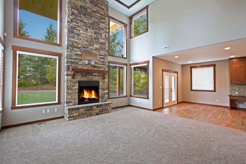 This is an example of an arts and crafts family room in Seattle with beige walls, carpet, a standard fireplace, a stone fireplace surround and a wall-mounted tv.