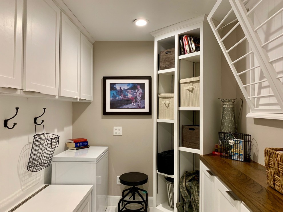 Design ideas for a small transitional u-shaped utility room in Houston with shaker cabinets, white cabinets, wood benchtops, grey walls, marble floors, a side-by-side washer and dryer, white floor and brown benchtop.