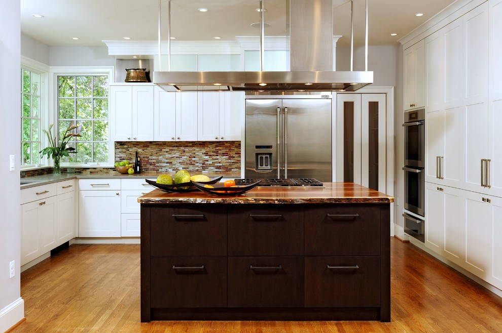Photo of a mid-sized transitional u-shaped eat-in kitchen in DC Metro with an undermount sink, shaker cabinets, dark wood cabinets, multi-coloured splashback, glass tile splashback, stainless steel appliances, light hardwood floors, with island and wood benchtops.