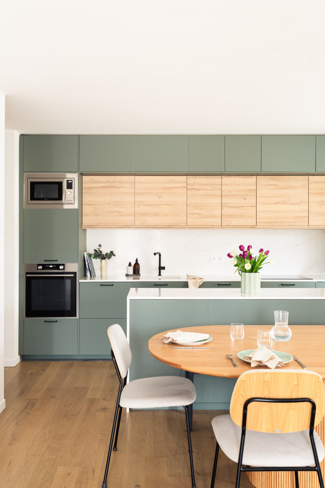 Mid-sized scandinavian single-wall open plan kitchen in Paris with an integrated sink, beaded inset cabinets, green cabinets, quartzite benchtops, white splashback, engineered quartz splashback, stainless steel appliances, light hardwood floors, with island and white benchtop.
