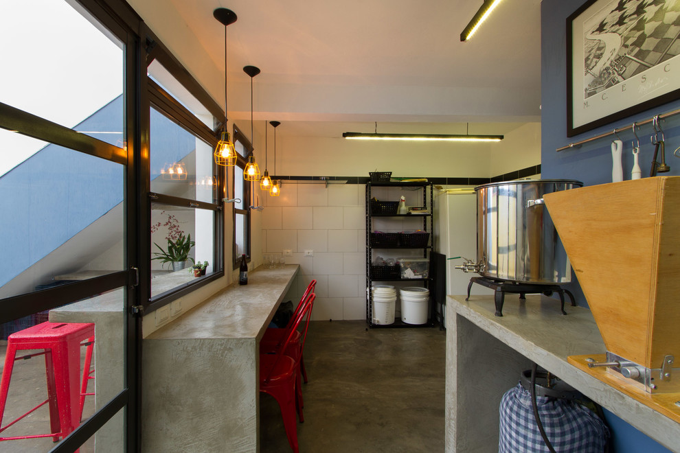 Mid-sized industrial l-shaped seated home bar in Other with a drop-in sink, flat-panel cabinets, blue cabinets, concrete benchtops, blue splashback, concrete floors, grey floor and grey benchtop.