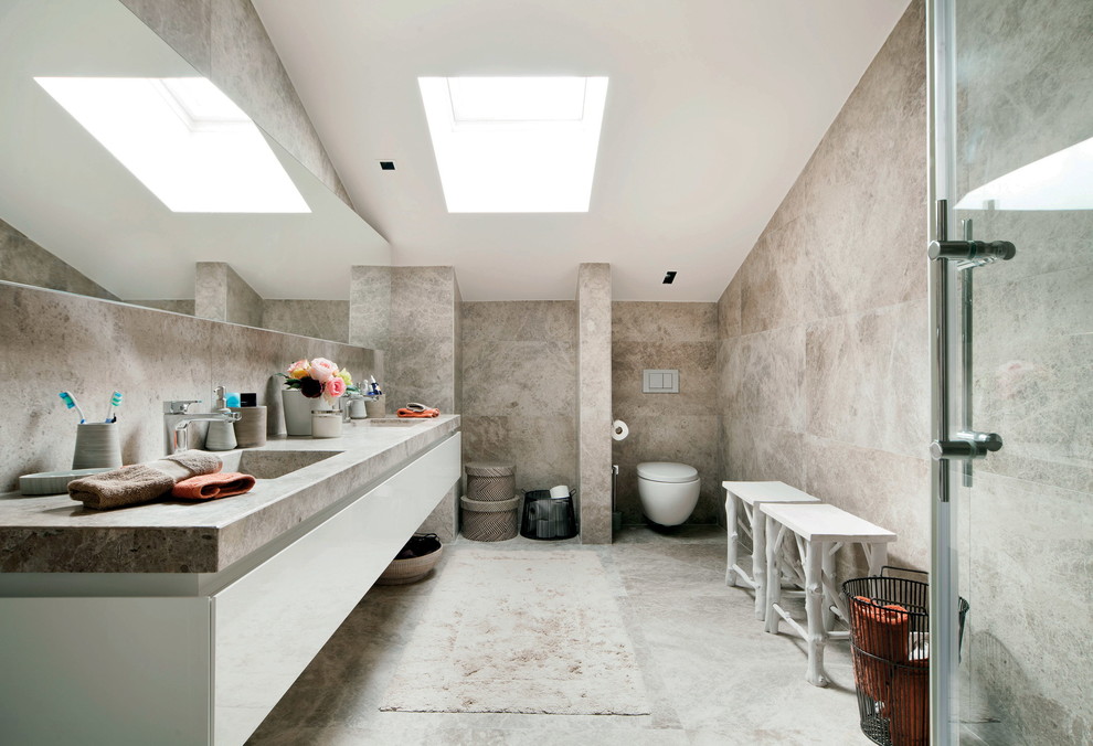 Contemporary bathroom in Other with an integrated sink, flat-panel cabinets, white cabinets, a wall-mount toilet, beige tile, beige walls and grey benchtops.