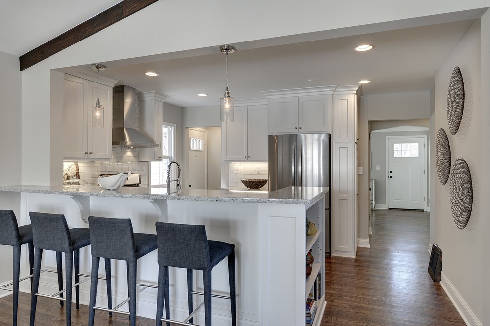 Design ideas for a small transitional l-shaped eat-in kitchen in Minneapolis with a farmhouse sink, flat-panel cabinets, white cabinets, granite benchtops, white splashback, ceramic splashback, stainless steel appliances and medium hardwood floors.