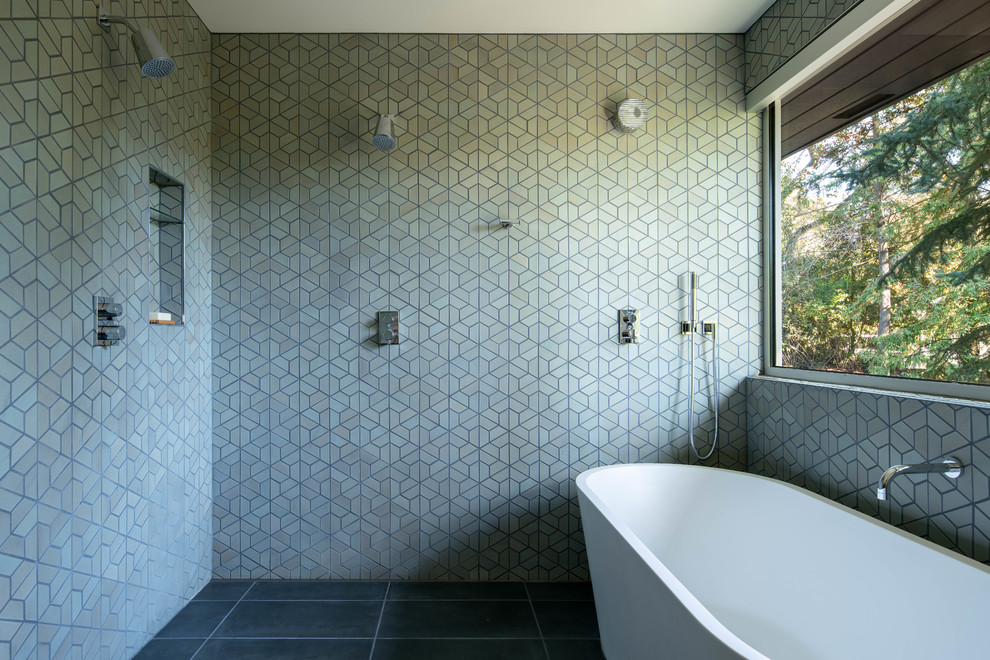 This is an example of a midcentury wet room bathroom in San Francisco with a freestanding tub, green tile and black floor.