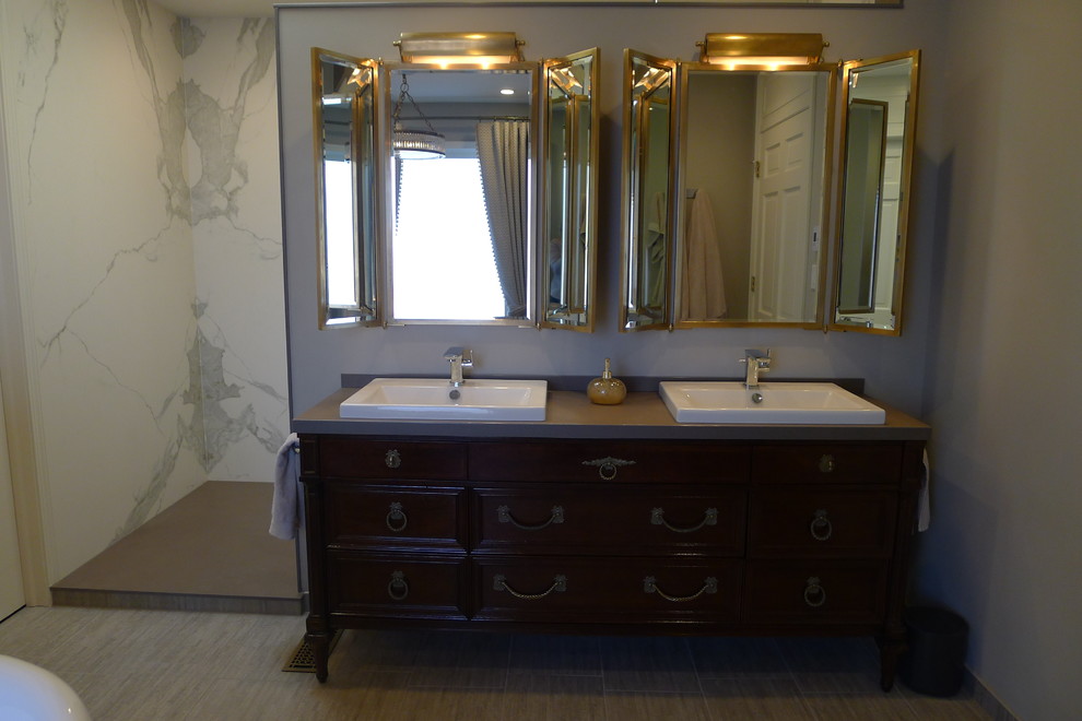 Large transitional master gray tile and porcelain tile porcelain tile freestanding bathtub photo in Indianapolis with a drop-in sink, furniture-like cabinets, dark wood cabinets, solid surface countertops, a one-piece toilet and gray walls