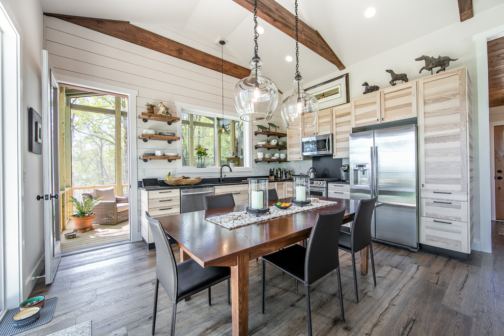 Example of a mountain style l-shaped dark wood floor and brown floor eat-in kitchen design with shaker cabinets, light wood cabinets, stainless steel appliances, no island and black countertops