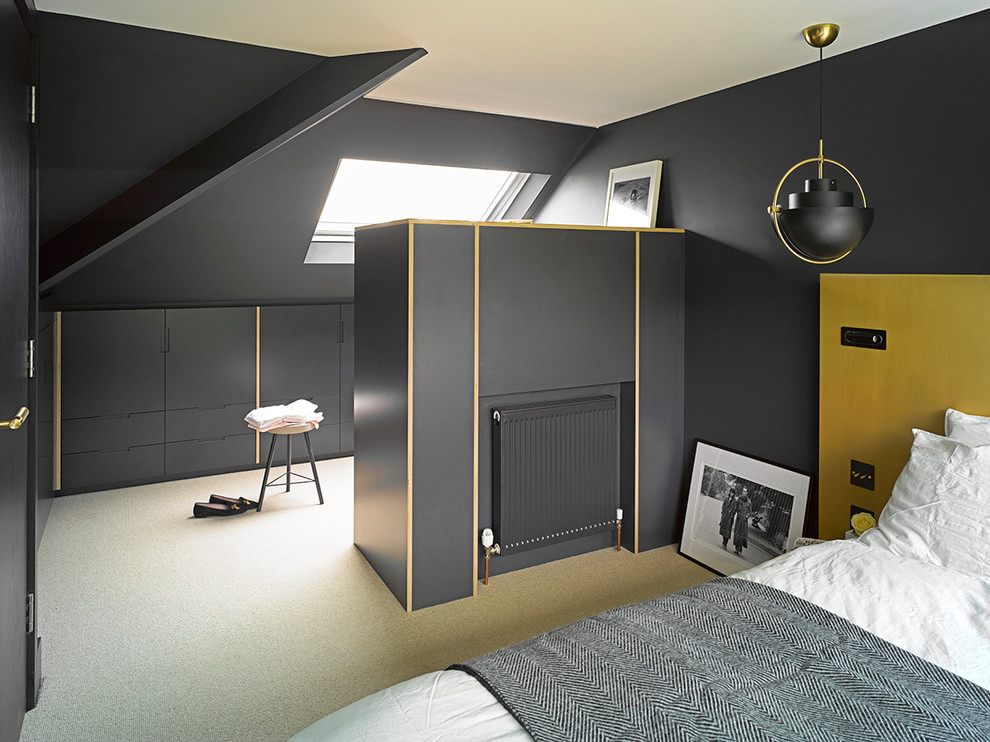 Photo of a mid-sized industrial bedroom in London with black walls and carpet.