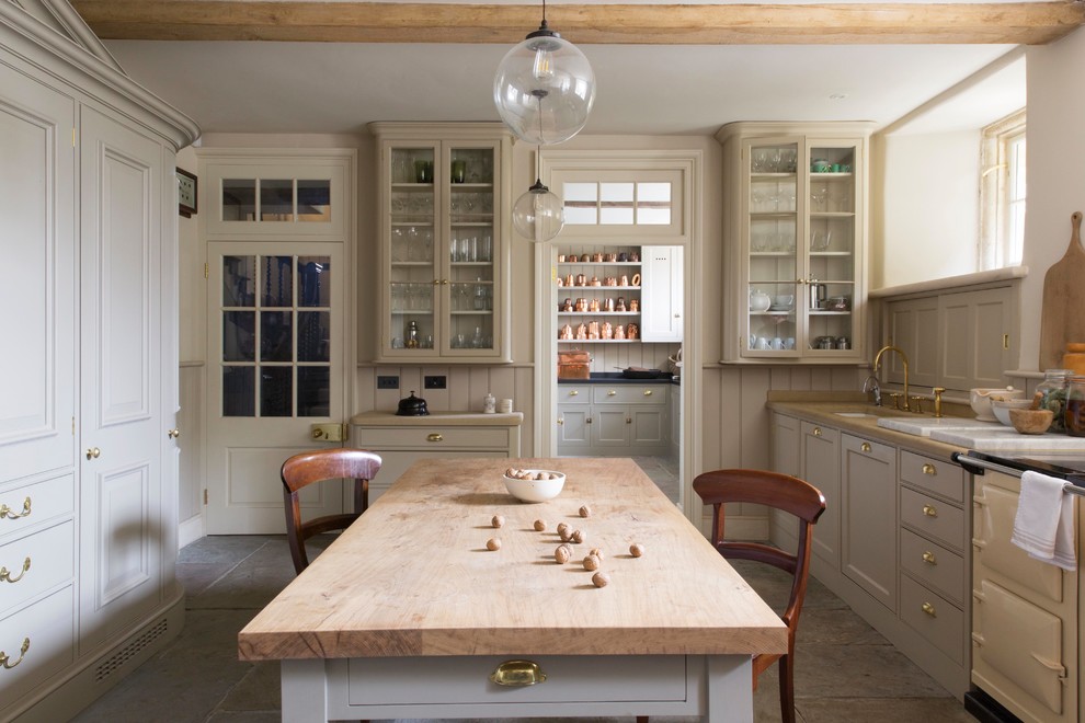 Inspiration for a country galley separate kitchen in London with with island, an undermount sink, shaker cabinets, beige cabinets, wood benchtops, beige splashback, timber splashback, coloured appliances and grey floor.