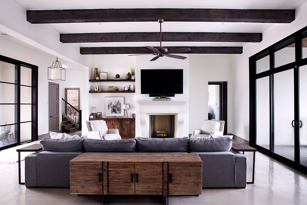 Example of a mid-sized transitional formal and open concept gray floor and concrete floor living room design in Austin with white walls, a standard fireplace, a wall-mounted tv and a plaster fireplace