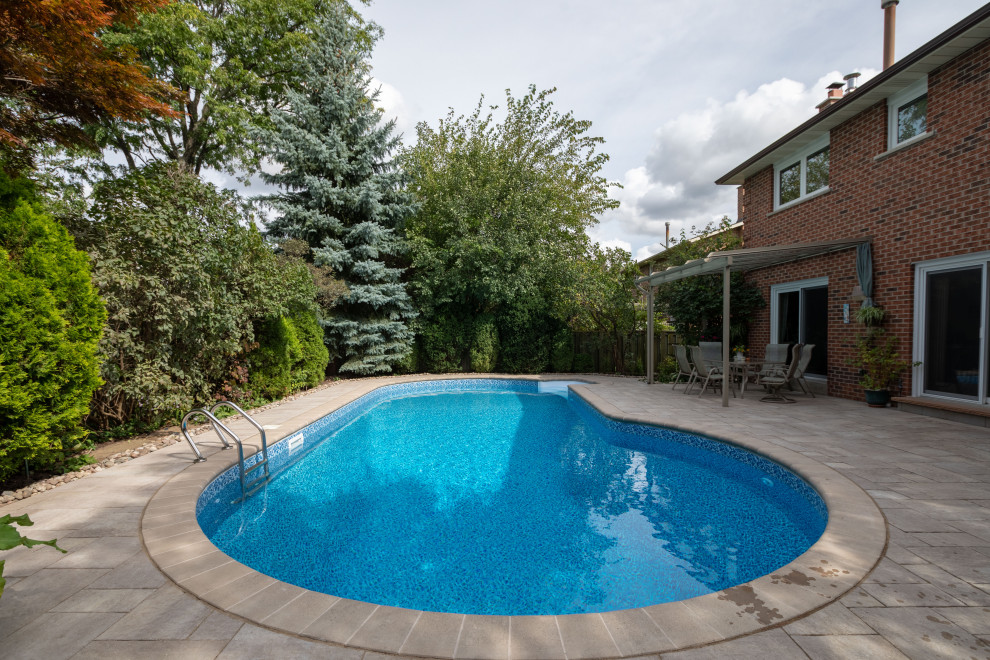 На фото: ландшафтный бассейн среднего размера, в форме фасоли на заднем дворе в стиле модернизм с мощением тротуарной плиткой с