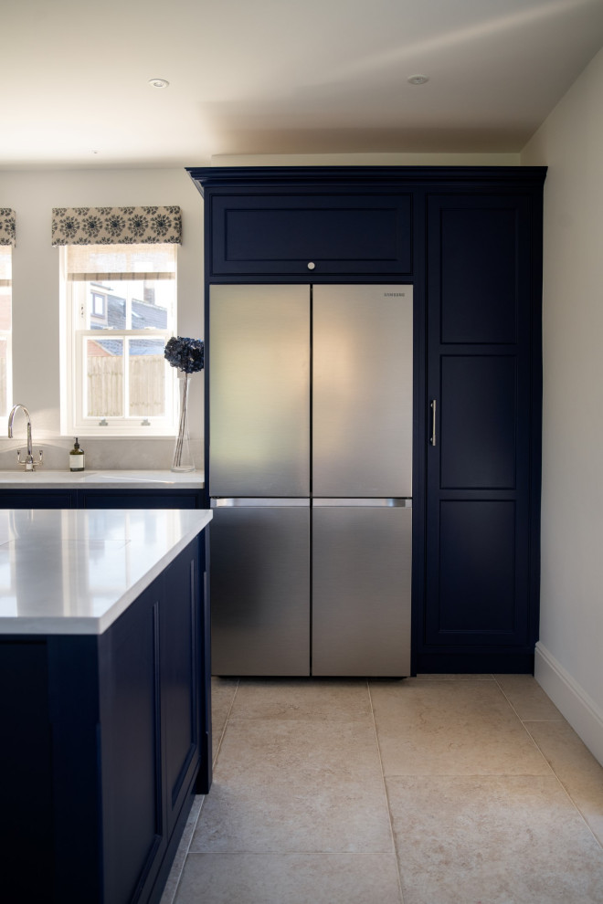 This is an example of a mid-sized industrial galley eat-in kitchen in Cambridgeshire with an integrated sink, shaker cabinets, blue cabinets, quartzite benchtops, stainless steel appliances, limestone floors, with island, grey floor and grey benchtop.
