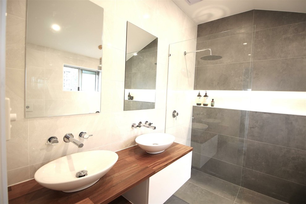 Design ideas for a modern master wet room bathroom in Brisbane with medium wood cabinets, a claw-foot tub, a wall-mount toilet, ceramic tile, cement tiles and wood benchtops.