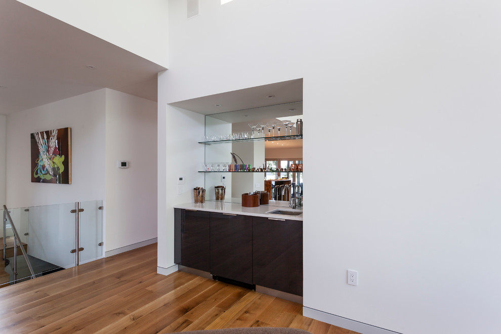 Inspiration for a mid-sized contemporary l-shaped light wood floor open concept kitchen remodel in Baltimore with an undermount sink, flat-panel cabinets, gray cabinets, gray backsplash, glass tile backsplash, stainless steel appliances and an island