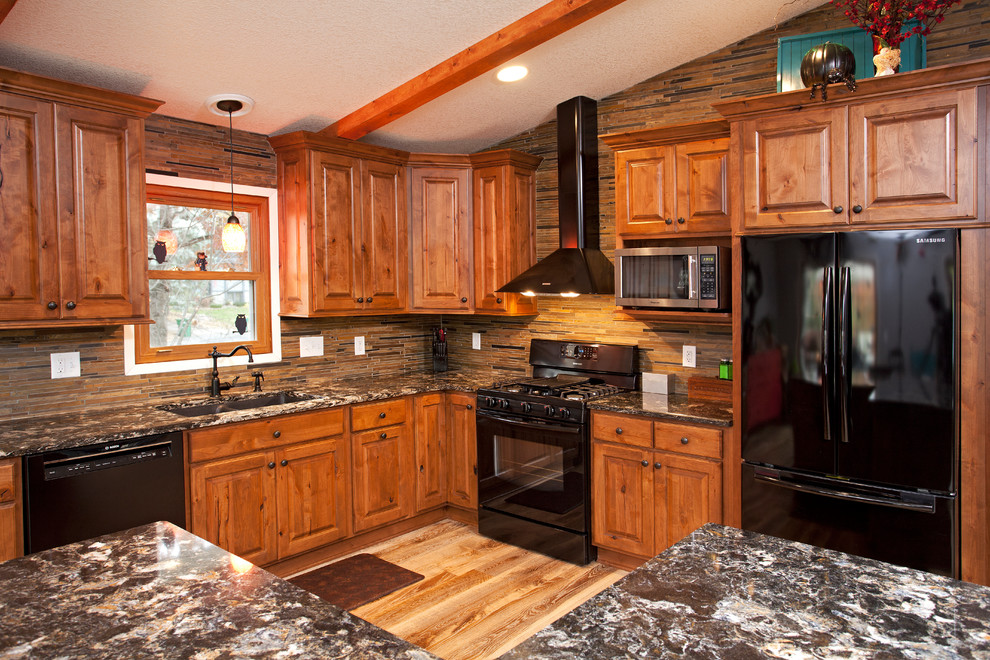 Mid-sized mountain style l-shaped light wood floor eat-in kitchen photo in Minneapolis with an undermount sink, raised-panel cabinets, medium tone wood cabinets, quartz countertops, green backsplash, stone tile backsplash, black appliances and an island