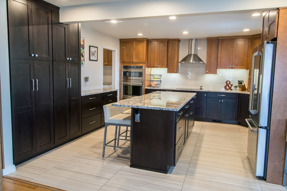 Large transitional u-shaped porcelain tile and gray floor eat-in kitchen photo with shaker cabinets, dark wood cabinets, granite countertops, white backsplash, subway tile backsplash, stainless steel appliances and an island