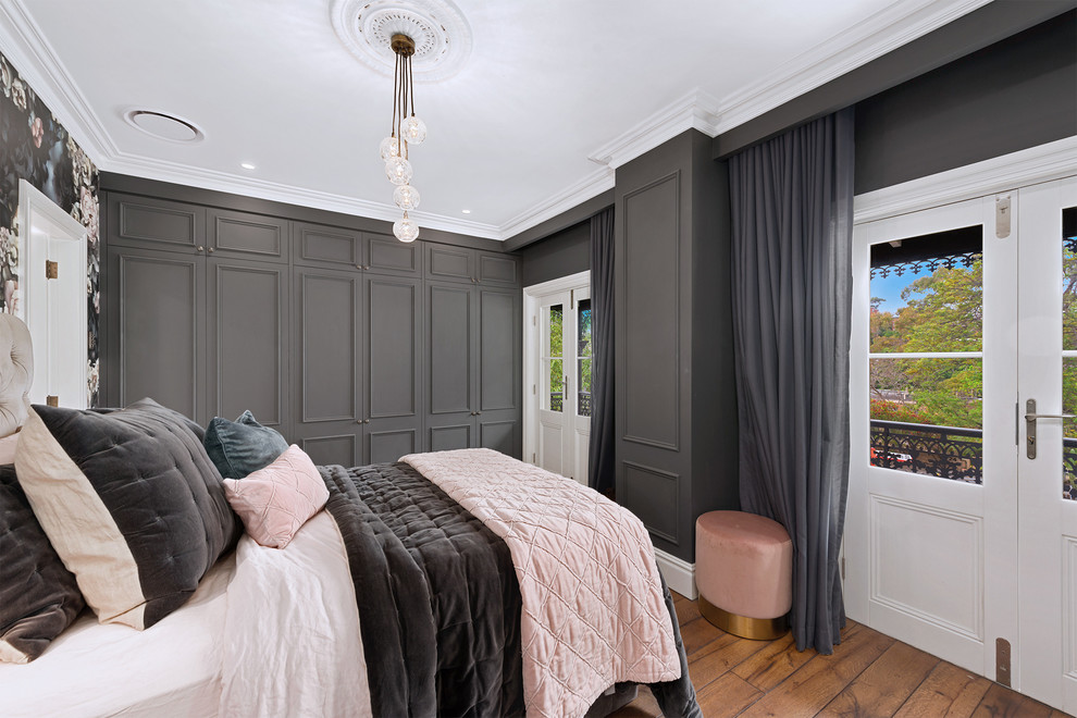 Photo of a transitional bedroom in Sydney with grey walls, medium hardwood floors and brown floor.