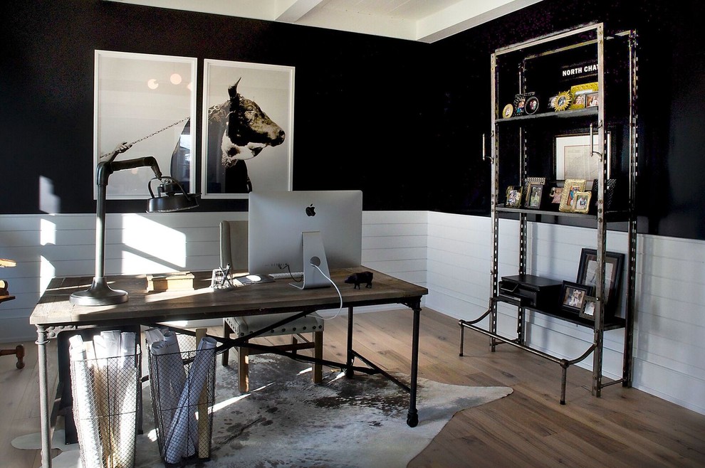 Photo of a mid-sized industrial study room in Other with black walls, light hardwood floors, a freestanding desk, no fireplace and brown floor.