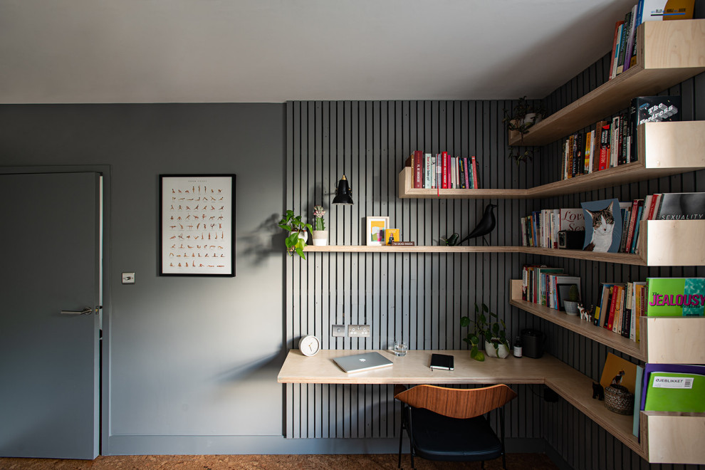 Bild på ett mellanstort minimalistiskt hemmabibliotek, med grå väggar, korkgolv, ett inbyggt skrivbord och brunt golv
