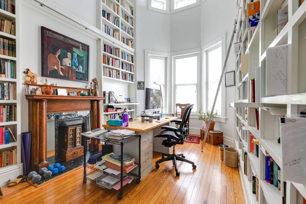 Cette image montre un bureau traditionnel de taille moyenne avec une bibliothèque ou un coin lecture, un mur blanc, un sol en bois brun, une cheminée standard, un manteau de cheminée en bois, un bureau indépendant et un sol marron.