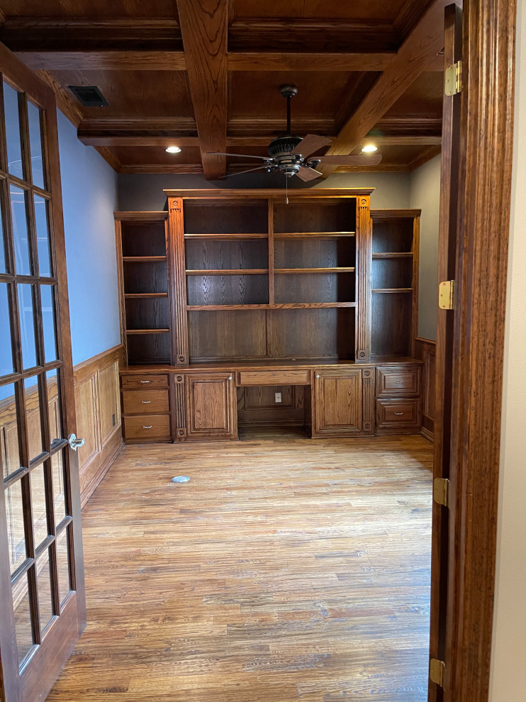 This is an example of a traditional study room in Dallas with blue walls, dark hardwood floors, a built-in desk, brown floor, coffered and panelled walls.