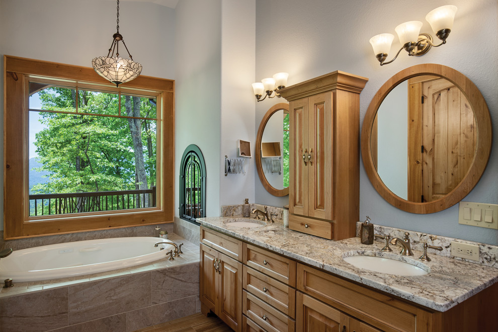 Photo of a country master bathroom in Other with light wood cabinets, a drop-in tub, grey walls, an undermount sink, multi-coloured benchtops and raised-panel cabinets.
