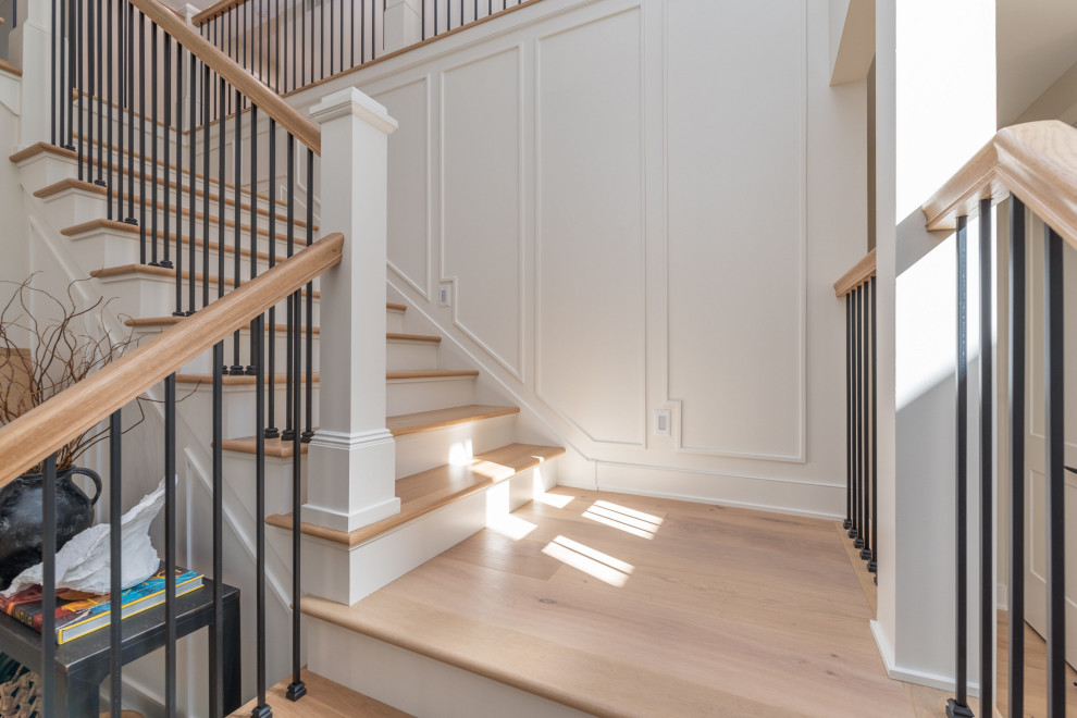 Classic wood metal railing staircase in Minneapolis with painted wood risers and panelled walls.