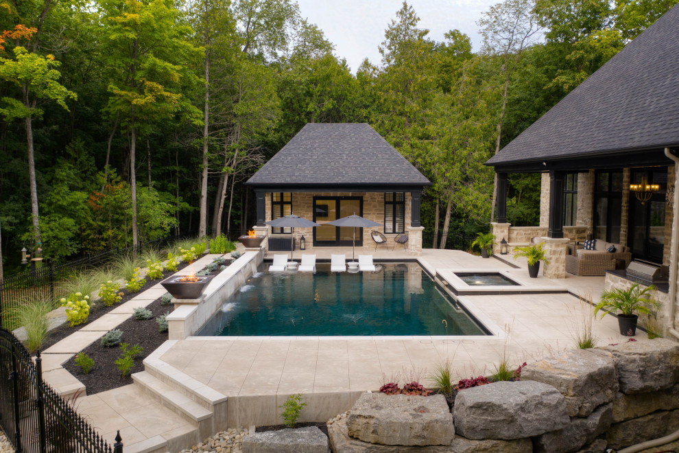 Aménagement d'un piscine avec aménagement paysager arrière classique de taille moyenne et rectangle avec du béton estampé.