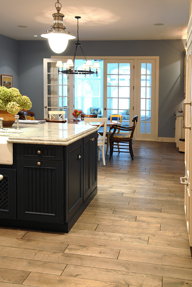 Inspiration for a large mediterranean u-shaped medium tone wood floor and brown floor eat-in kitchen remodel in Chicago with a farmhouse sink, beaded inset cabinets, white cabinets, granite countertops, white backsplash, porcelain backsplash, stainless steel appliances, an island and white countertops