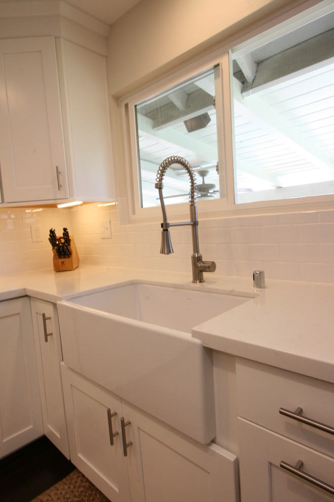 Inspiration for a large transitional u-shaped dark wood floor eat-in kitchen remodel in Orange County with a farmhouse sink, shaker cabinets, white cabinets, quartz countertops, white backsplash, ceramic backsplash, stainless steel appliances and an island