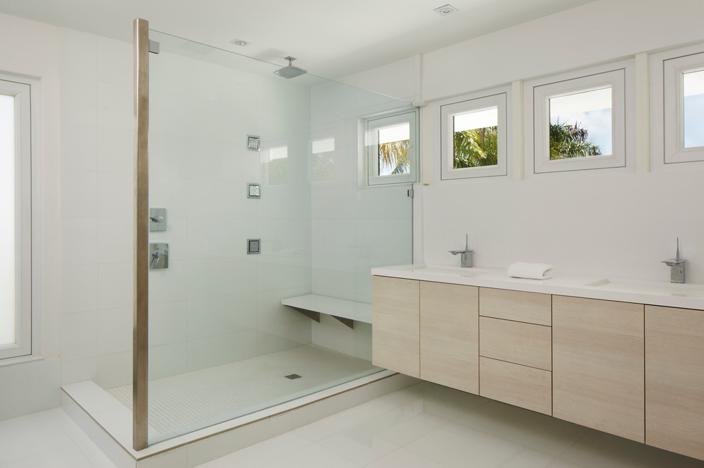 Photo of a contemporary bathroom in Miami with an undermount sink, flat-panel cabinets, light wood cabinets, a corner shower and white tile.