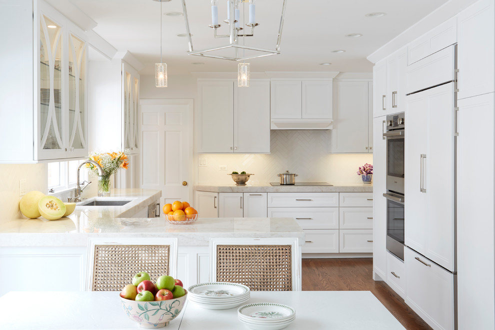 Inspiration for a mid-sized transitional u-shaped eat-in kitchen in Chicago with an undermount sink, white cabinets, quartzite benchtops, white splashback, stainless steel appliances, white benchtop, recessed-panel cabinets, dark hardwood floors, a peninsula and brown floor.
