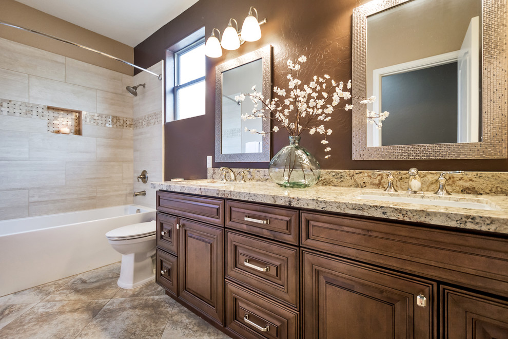 Design ideas for a mid-sized traditional kids bathroom in Phoenix with raised-panel cabinets, brown cabinets, a drop-in tub, a shower/bathtub combo, a one-piece toilet, beige tile, porcelain tile, brown walls, a drop-in sink, granite benchtops and a shower curtain.