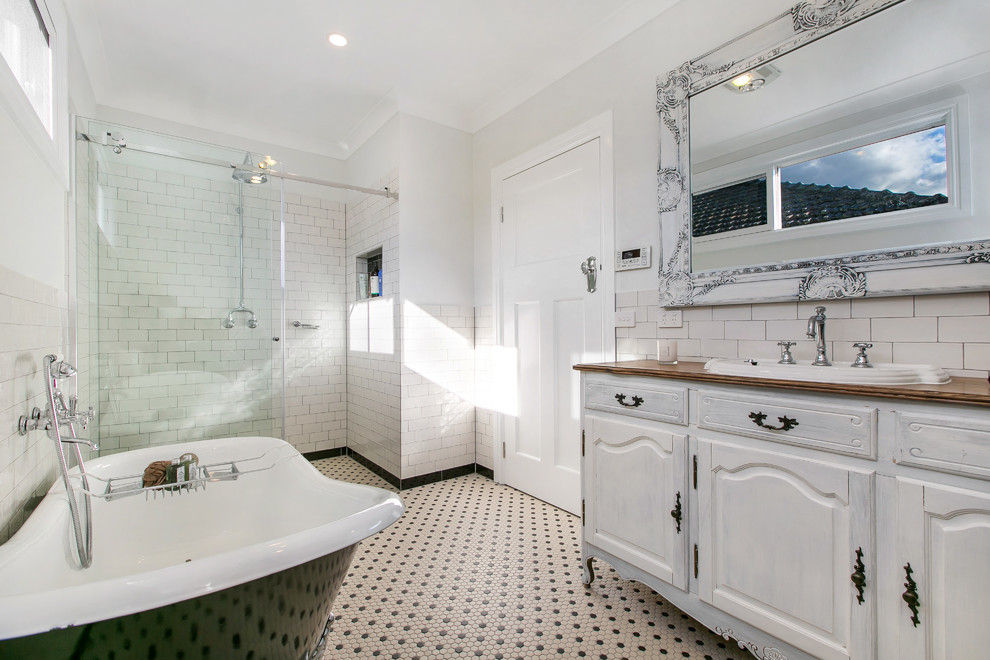 Inspiration for a traditional master bathroom in Melbourne with an integrated sink, furniture-like cabinets, distressed cabinets, wood benchtops, a claw-foot tub, a two-piece toilet, multi-coloured tile, porcelain tile, white walls, mosaic tile floors and an alcove shower.