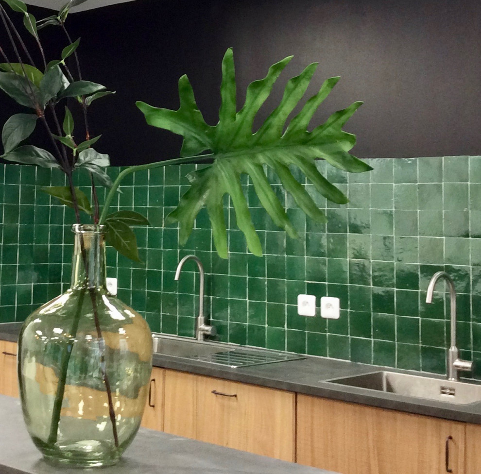 This is an example of a tropical kitchen in Paris with an undermount sink, flat-panel cabinets, light wood cabinets, laminate benchtops, green splashback, panelled appliances, ceramic floors and grey benchtop.
