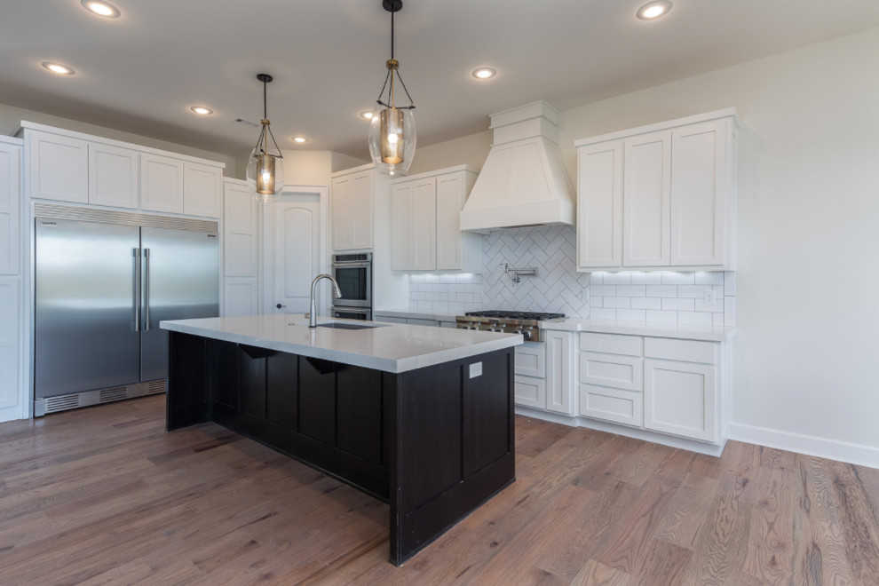 Open concept kitchen - mid-sized transitional l-shaped dark wood floor and brown floor open concept kitchen idea with an undermount sink, white backsplash, subway tile backsplash, stainless steel appliances, shaker cabinets, white cabinets, solid surface countertops and an island