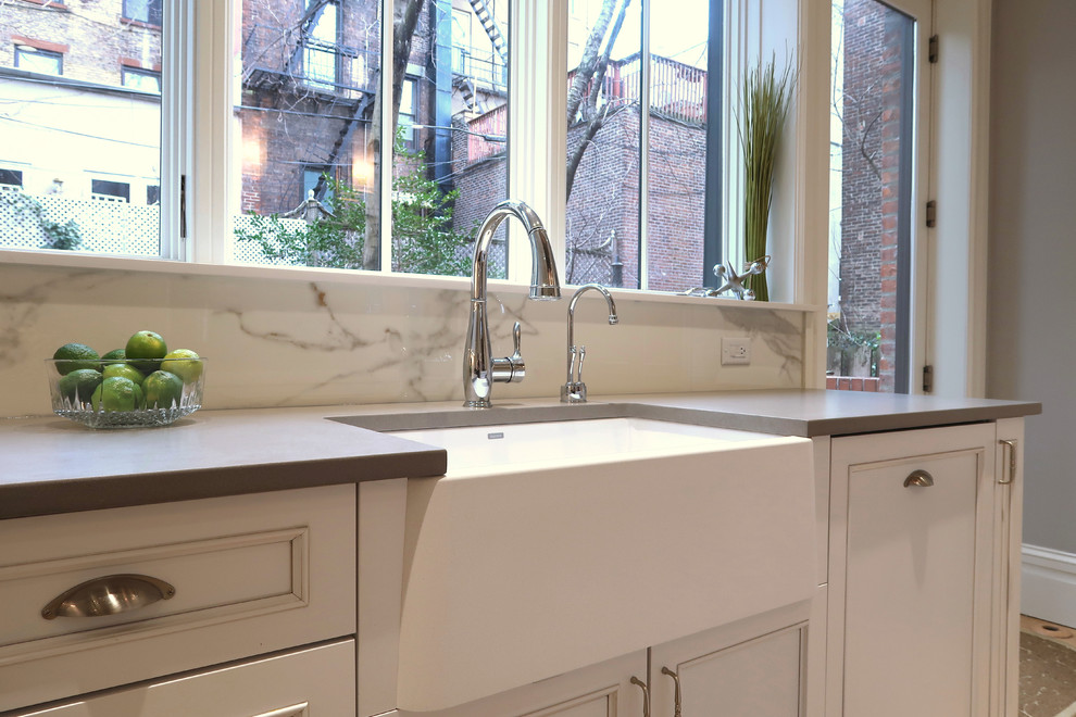 Example of a small transitional u-shaped light wood floor and brown floor enclosed kitchen design with a farmhouse sink, recessed-panel cabinets, white cabinets, quartz countertops, yellow backsplash, stone slab backsplash, stainless steel appliances, an island and white countertops