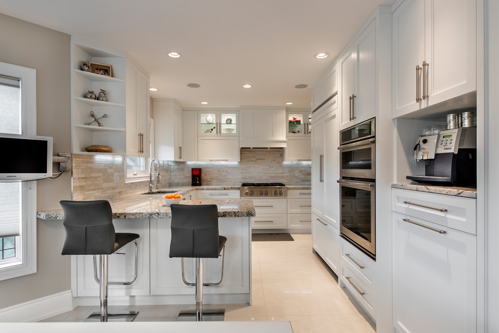 Design ideas for a mid-sized contemporary u-shaped eat-in kitchen in Toronto with an undermount sink, shaker cabinets, white cabinets, granite benchtops, brown splashback, stone tile splashback, panelled appliances, porcelain floors, a peninsula, grey floor and brown benchtop.