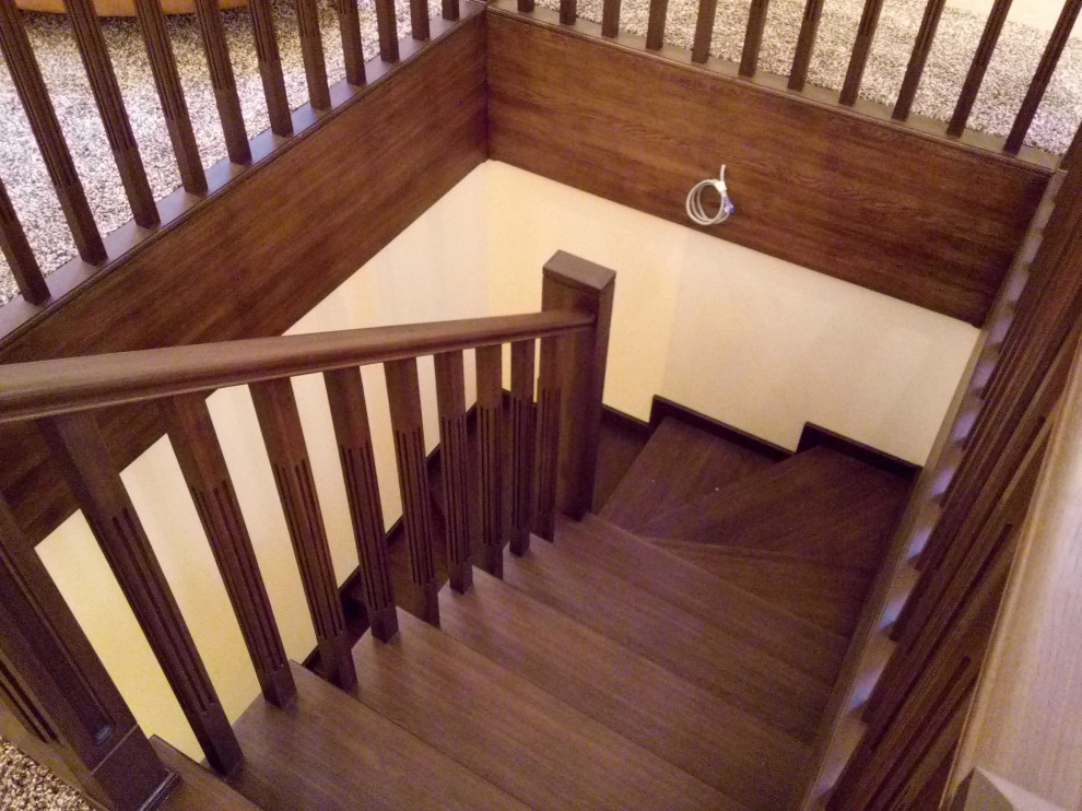 他の地域にある高級な広いトラディショナルスタイルのおしゃれな階段 (木の蹴込み板、木材の手すり) の写真