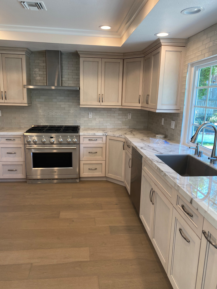 Mid-sized contemporary u-shaped eat-in kitchen in Orange County with an undermount sink, recessed-panel cabinets, grey cabinets, quartzite benchtops, grey splashback, subway tile splashback, stainless steel appliances, light hardwood floors, no island, brown floor, white benchtop and coffered.
