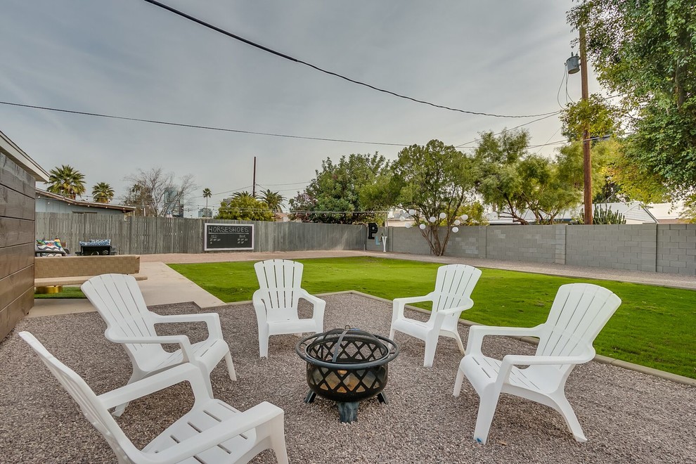 This is an example of a mid-sized midcentury backyard patio in Phoenix with a fire feature, gravel and no cover.