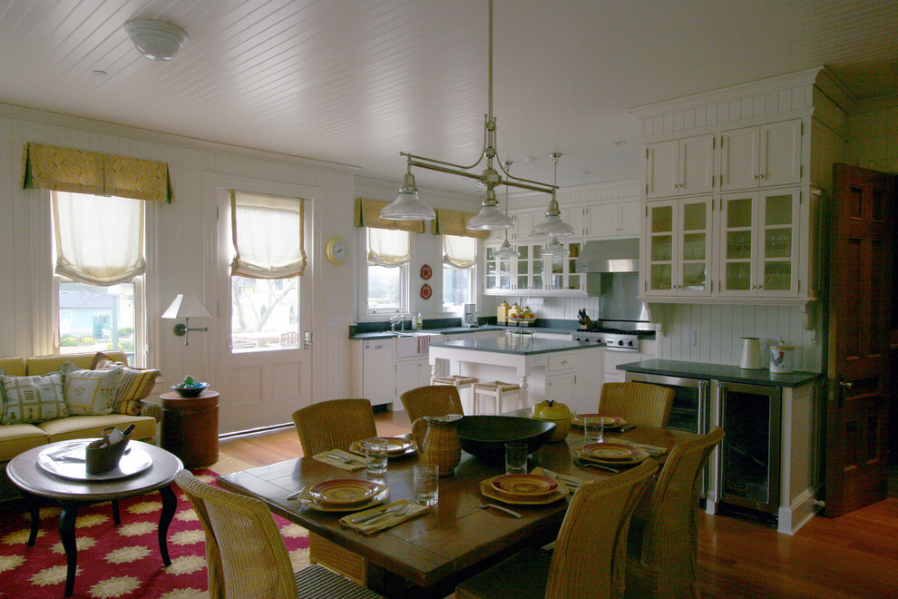 Photo of a mid-sized traditional u-shaped eat-in kitchen in Boston with a single-bowl sink, glass-front cabinets, white cabinets, white splashback, white appliances, medium hardwood floors and with island.